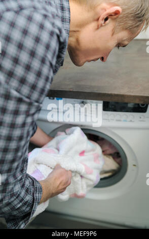 Mann nimmt die Dinge mit der Waschmaschine gewaschen. Stockfoto