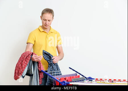 Der Mann nimmt die Dinge aus Wäschetrockner Kleidung. Stockfoto