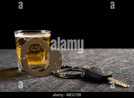 Autoschlüssel und Handschellen in der Tasse Bier Konzept der illegalen betrunkenen Fahrens Stockfoto