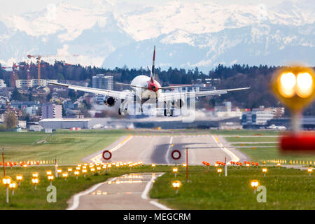 Flughafen Zürich ZRH mit Flugzeug bei der Landung. Dahinter die Schnee bedeckten Berge der Alpen. Stockfoto