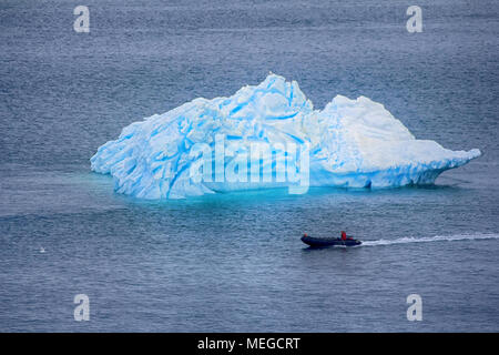 Schwere Land. Rauhe Arktis. Arctic Ocean bei ruhigem Wetter, Iceberg und polar Mann (Iceman) auf dem Motorboot in helle warme Kleidung Stockfoto