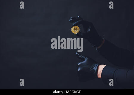Bitcoins auf dem Arm Hände in schwarz Handschuhe platzierten Symbol anzeigen. Stockfoto