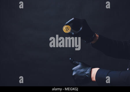 Bitcoins auf dem Arm Hände in schwarz Handschuhe platzierten Symbol anzeigen. Stockfoto