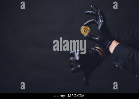 Bitcoins auf dem Arm Hände in schwarz Handschuhe platzierten Symbol anzeigen. Stockfoto