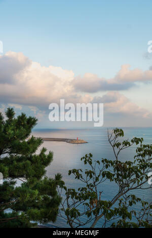 Leuchtturm und cloudscape im Ozean mit Wellenbrecher und violetten Himmel bei Sonnenuntergang an der Küste, Yongmeori Sanbang-ro, Jeju Island, South Korea Stockfoto