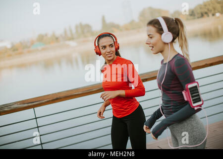 Zwei junge Frauen, die durch den Fluss am Morgen läuft Stockfoto