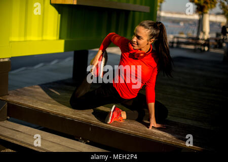 Junge Frau Übungen auf der Promenade nach der Ausführung am Morgen Stockfoto