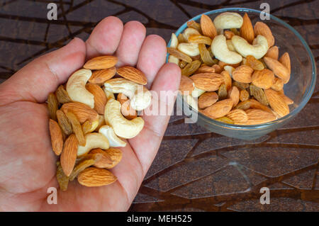 Die Muttern in der Palme der Hand Nüsse in der Schale braun Tabelle cashewkerne Mandeln Rosinen Stockfoto