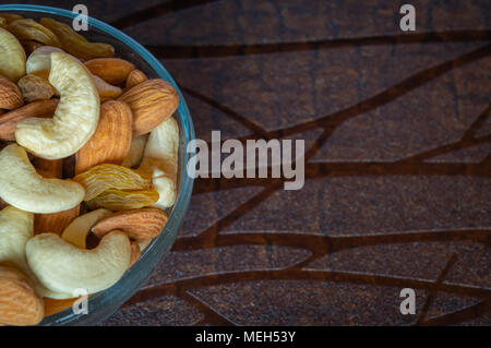 Nahaufnahme Blick von oben auf die Nüsse cashew Mandeln Rosinen in eine Schüssel auf hölzernen Tisch Platz für Text Stockfoto