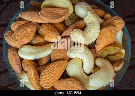 Nahaufnahme Blick von oben auf die Nüsse cashew Mandeln Rosinen in eine Schüssel geben. Stockfoto