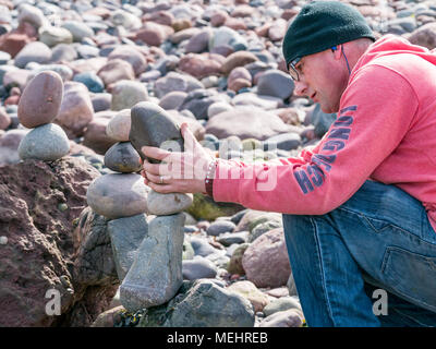 Dunbar, Schottland, 22. April 2018. Auge Cave Strand, Dunbar, East Lothian, Schottland, Vereinigtes Königreich. In der zweiten Europäischen Stein stacking Meisterschaft, von Dunbar Street Art Trail organisiert. Die abschließende Konkurrenz war die meisten künstlerischen Stein Balance zu schaffen. Ein Konkurrent baut ein Stein ausgewogene Arbeit der Kunst Stockfoto