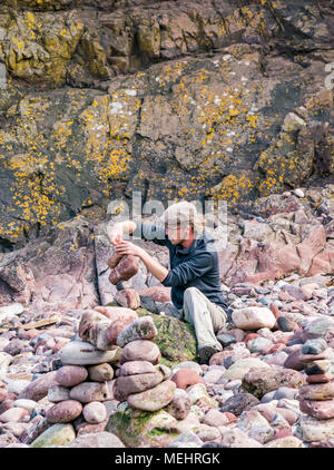 Dunbar, Schottland, 22. April 2018. Auge Cave Strand, Dunbar, East Lothian, Schottland, Vereinigtes Königreich. In der zweiten Europäischen Stein stacking Meisterschaft, von Dunbar Street Art Trail organisiert. Die abschließende Konkurrenz war die meisten künstlerischen Stein Balance zu schaffen. Philip Wachmann, ein Wettbewerber aus Österreich, schafft ein ausgewogenes Kunstwerk aus Stein Stockfoto