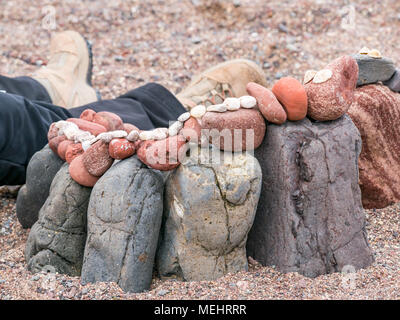 Dunbar, Schottland, 22. April 2018. Auge Cave Strand, Dunbar, East Lothian, Schottland, Vereinigtes Königreich. In der zweiten Europäischen Stein stacking Meisterschaft, von Dunbar Street Art Trail organisiert. Die abschließende Konkurrenz war die meisten künstlerischen Stein Balance zu schaffen. Stein ausgewogene Arbeit mit der Beine und Stiefel von der Person, die es Gebäude Stockfoto