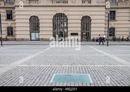 Berlin, Deutschland. 16 Apr, 2018. Ein Blick auf den Bebelplatz in Berlin, Deutschland, am Montag, 16. April 2018. Der Bebelplatz Memorial 1995 eingeweiht wurde, und es ist die Arbeit des israelischen Künstlers Micha Ullman. Es handelt sich um eine Glasplatte in Pflastersteine, und darunter gibt es einen unterirdischen Raum mit leeren Bücherregalen. Bebelplatz ist als Standort eines der berüchtigten NS-Bücherverbrennung Zeremonien, am 10. Mai 1933 statt. Mitglieder der Nationalsozialistischen Deutschen Studentenschaft und ihre Professoren verbrannt etwa 20.000 Bücher als Teil einer bundesweiten Aktion" gegen die un-deutschen Geist." Ein p Stockfoto