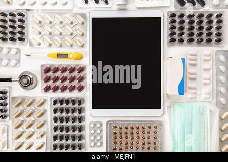 Digitale Tablet von bunten Pillen auf Tisch umgeben Stockfoto