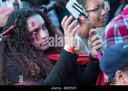 Eine junge Frau in Zombie Make-up und trägt eine gefälschte Messer durch den Kopf, nimmt eine selfie am Cherokee Zombie Fest am 17. Oktober 2015 im Bezirk, GA. Stockfoto