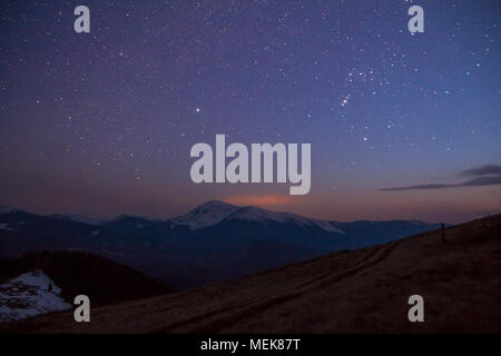 Majestätischen Blick auf fantastischen Sternenhimmel dunkle Himmel über herrliche Karpaten bedeckt mit immergrünen Wald und schneebedeckte Berge in der Ferne. Brea Stockfoto