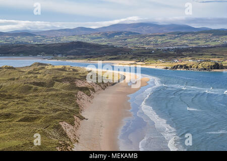 Ein weisser Sandstrand bei Ebbe mit Gras überwachsen hinter den Dünen. Stockfoto