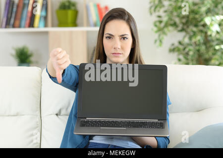 Anwry Frau zeigt einen leeren Bildschirm auf einer Couch im Wohnzimmer zu Hause sitzen Stockfoto