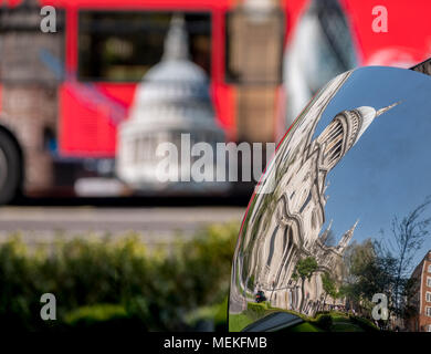 Verzerrte Widerspiegelung der St Paul's Cathedral, London, UK, in glänzendem Metall Oberfläche der Spiegel Skulptur spiegelt, verschwommenes roten Bus im Hintergrund. Stockfoto