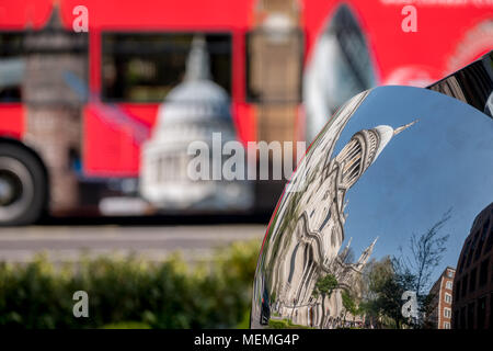 Verzerrte Widerspiegelung der St Paul's Cathedral, London, UK, in glänzendem Metall Oberfläche der Spiegel Skulptur spiegelt, verschwommenes roten Bus im Hintergrund. Stockfoto