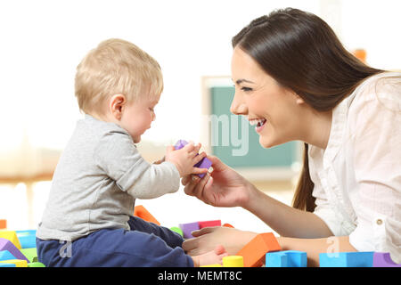 Seitliche Sicht auf eine glückliche Mutter und Sohn mit Spielzeug spielen auf dem Boden Stockfoto