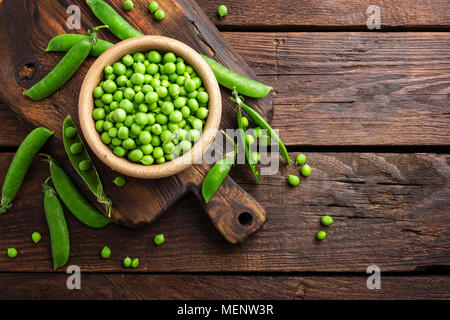 Grüne Erbsen in Hülsen und in Houten auf Tisch geschält Stockfoto