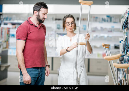 Mann mit Krücken in der Apotheke Stockfoto