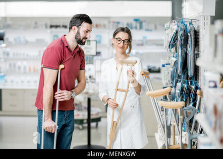 Mann mit Krücken in der Apotheke Stockfoto