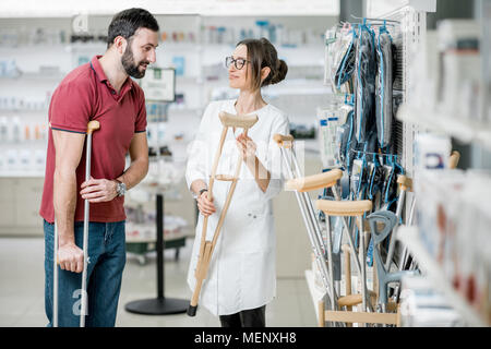 Mann mit Krücken in der Apotheke Stockfoto