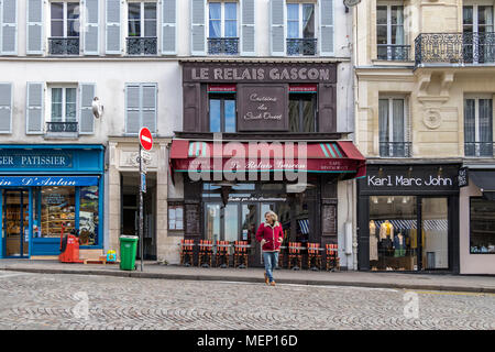 Ein Mann kreuzt die Straße draußen Le Relais Gascon Restaurant, Rue des Abbesses, Montmartre, Paris, Frankreich Stockfoto