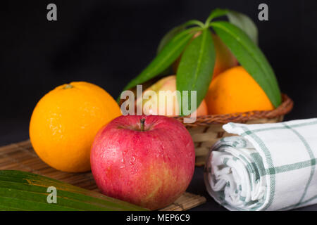 Äpfel mit Orangen auf Holz, Blech und Holz Warenkorb im schwarzen All Stockfoto