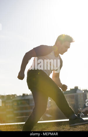 Junge männliche parkour Sportler führt akrobatische Sprünge vor der Skyline Stockfoto