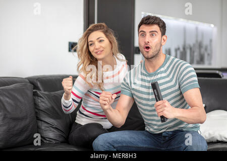 Nettes Paar aufgeregt und glücklich auf der Suche nach Ihrer Lieblingsfußballmannschaft einen Touchdown erzielte Stockfoto