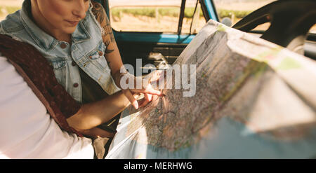 Glückliches junges Paar an eine Karte im Auto sitzen. Lächelnd Mann und Frau mit Karte auf Road Trip. Stockfoto