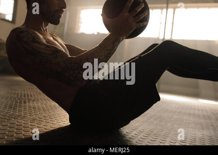 Muskulöse mann Trainieren mit medizinball im Fitnessstudio. Junger Mann tun mit Fitness Ball Workout. Stockfoto