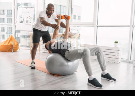 Schöne starke Mann lag auf der med-Kugel Stockfoto