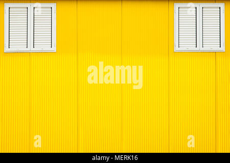 Die beiden Fenster Fensterläden auf Gelb sonnigen Wand gesperrt. Stockfoto