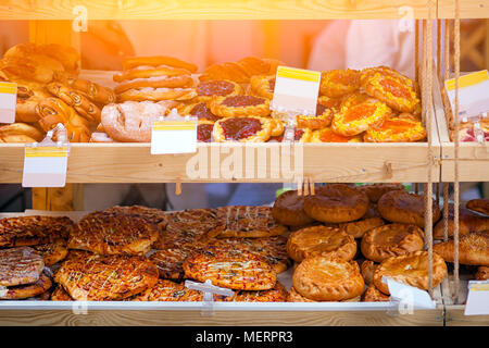Schaufenster einer Bäckerei mit frischem Gebäck: Pizza, Brötchen mit Beeren und Mohn, Torte mit Fleisch Stockfoto