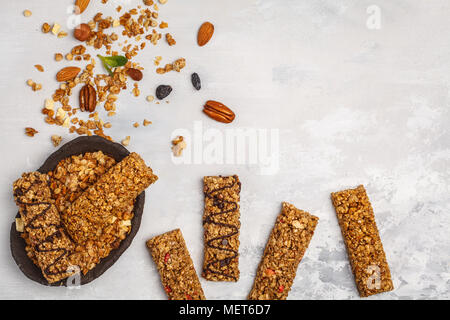 Müsliriegel und Zutaten. Gesunde süße Nachspeise Snack. Vegan Müsliriegel mit Nüssen, Schokolade und Beeren auf einem weißen Hintergrund. Ansicht von oben, Kopieren s Stockfoto