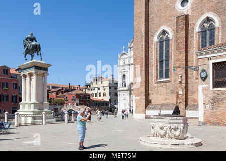 Ältere Frau Touristen fotografieren einer mittelalterlichen Pozzo oder auch Kopf, Campo Santi Giovanni e Paolo, Castello, Venedig, Venetien, Italien. Statue von Bartolomeo Stockfoto