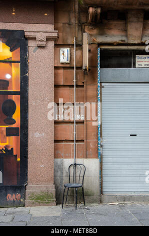 GLASGOW, Schottland - 18. SEPTEMBER 2014: ein Stahl Stuhl links außen auf einem Glasgow Seitenstraße. Stockfoto