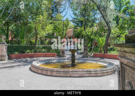 Heitere Sicht auf Benito Juarez Park, mit Bäumen, Steinen, Brunnen, Säulen und Steinweg, an einem sonnigen Tag, in San Miguel de Allende, Mexiko Stockfoto