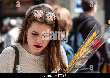 Barcelona, Spanien. 23. April 2018. Ein junges Mädchen ist gesehen Blick auf Bücher in den Ställen in der Nähe von Las Ramblas. Catalunya feiert den "Tag des Sant Jordi", dem Tag der Bücher und Rosen. Catalunya hofft zu erreichen, die Zahl von 7 Millionen Rosen verkauft. Es ist Tradition eine Rose oder ein Buch bei Liebhabern zu geben. Zahlreiche literarische Autoren signieren ihre Bücher der Öffentlichkeit auf die Straße. Credit: SOPA Images Limited/Alamy leben Nachrichten Stockfoto