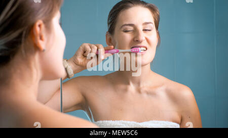 Junge schläfrig, brünette Frau, die ihre Zähne putzen am Morgen Stockfoto