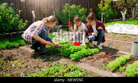 Foto von zwei Mädchen im Teenageralter mit Mutter im Garten arbeiten Stockfoto