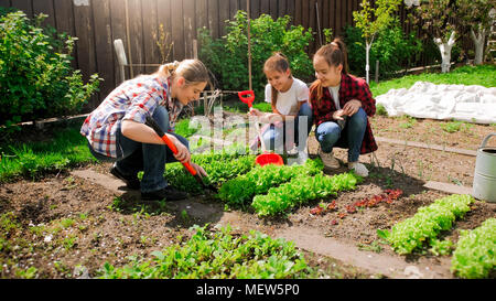 Glückliche junge Frau mit Töchtern Samen im Garten Stockfoto