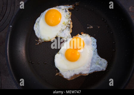 Ein Doppel-yolked Ei und ein normales Ei mit einem Eigelb zusammen Braten in einer nicht klebende Pan. Stockfoto