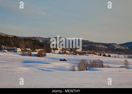 Die niedrige Winter Sonne scheint auf eine verschneite Dorf in Anundsjoe, Schweden. Stockfoto