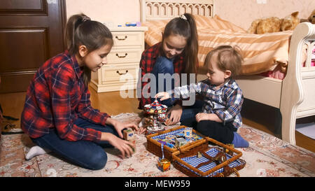 Zwei älteren Mädchen spielen mit Kleinkind Junge im Schlafzimmer Stockfoto